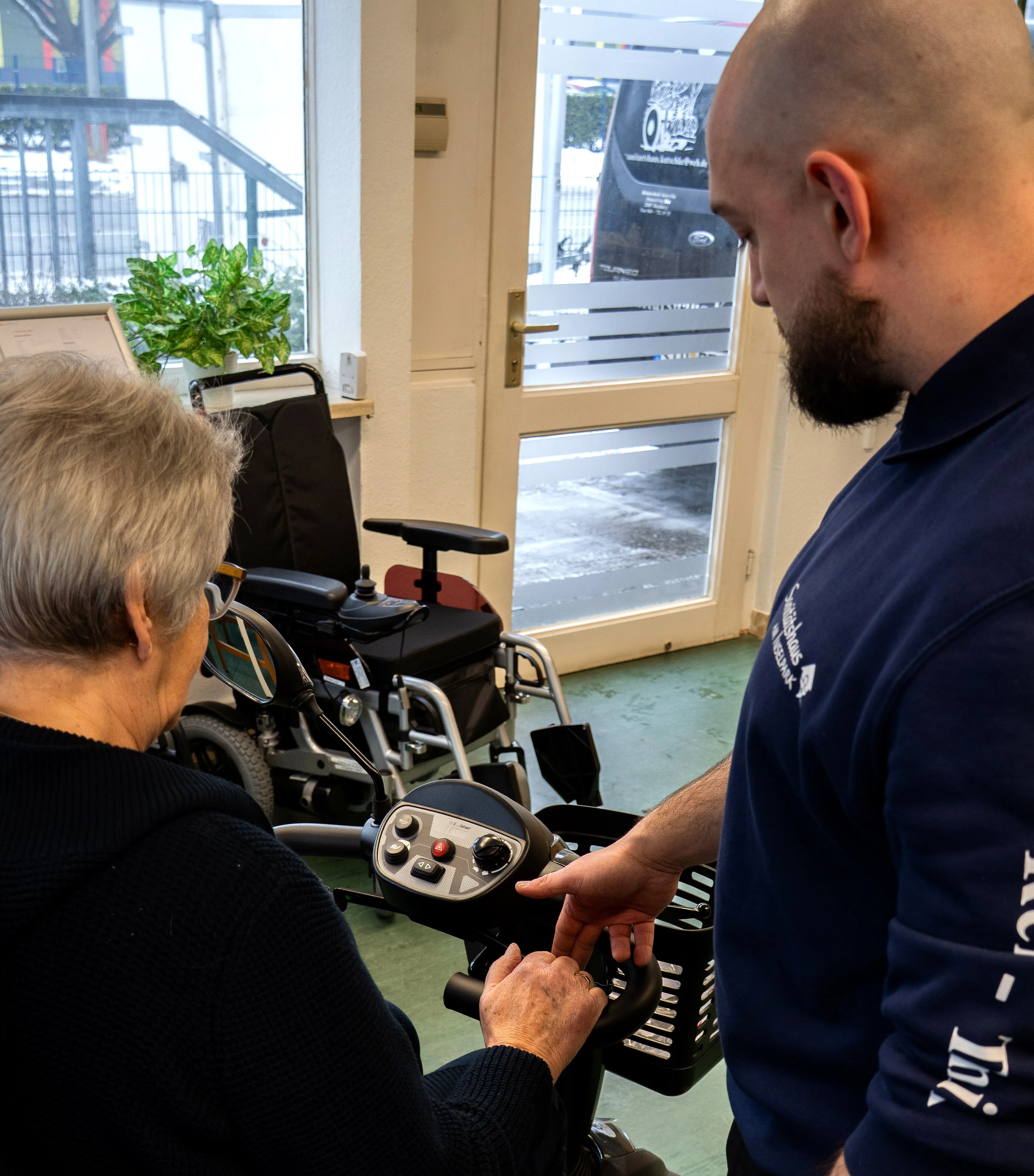 Persönliche Beratung im Sanitätshaus Kutschke: Ein Mitarbeiter erklärt einer Kundin die Bedienung ihres Elektromobils.